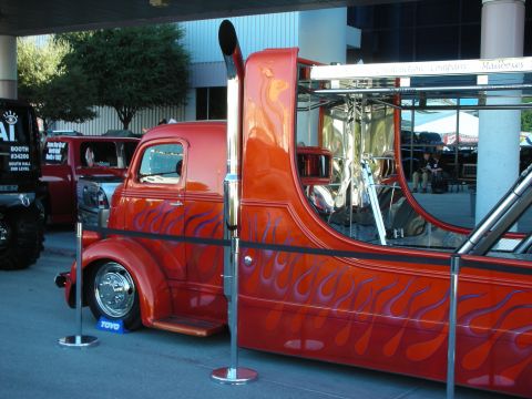 1998 Ford Crown Victoria - A custom truck with flame graphics and a large exhaust pipe is displayed, with another vehicle partially visible in the background.