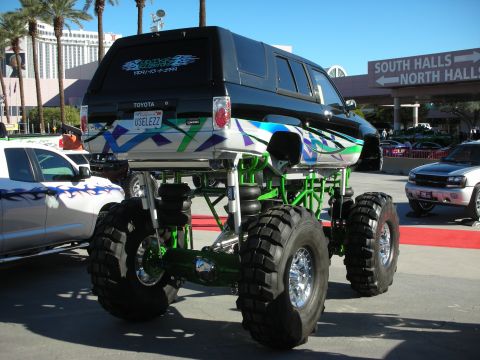 1998 Ford Crown Victoria - A heavily modified Toyota SUV with oversized tires and custom graphics is displayed outdoors.