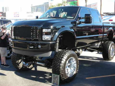 1998 Ford Crown Victoria - A heavily modified black Ford F-250 truck is displayed at an outdoor event.