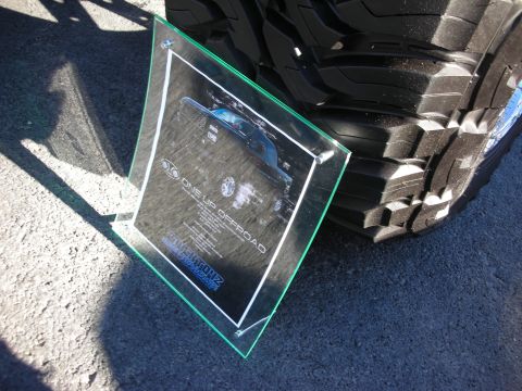 1998 Ford Crown Victoria - Glass display with truck image and text from One Up Offroad, positioned next to a large tire.