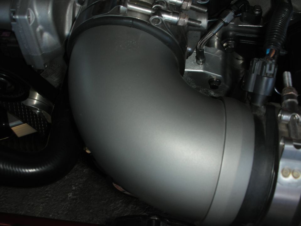 close-up of a silver intake pipe connected to engine components