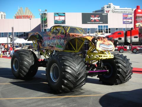 1998 Ford Crown Victoria - A custom monster truck with a distinctive paint job and large tires is displayed outdoors.