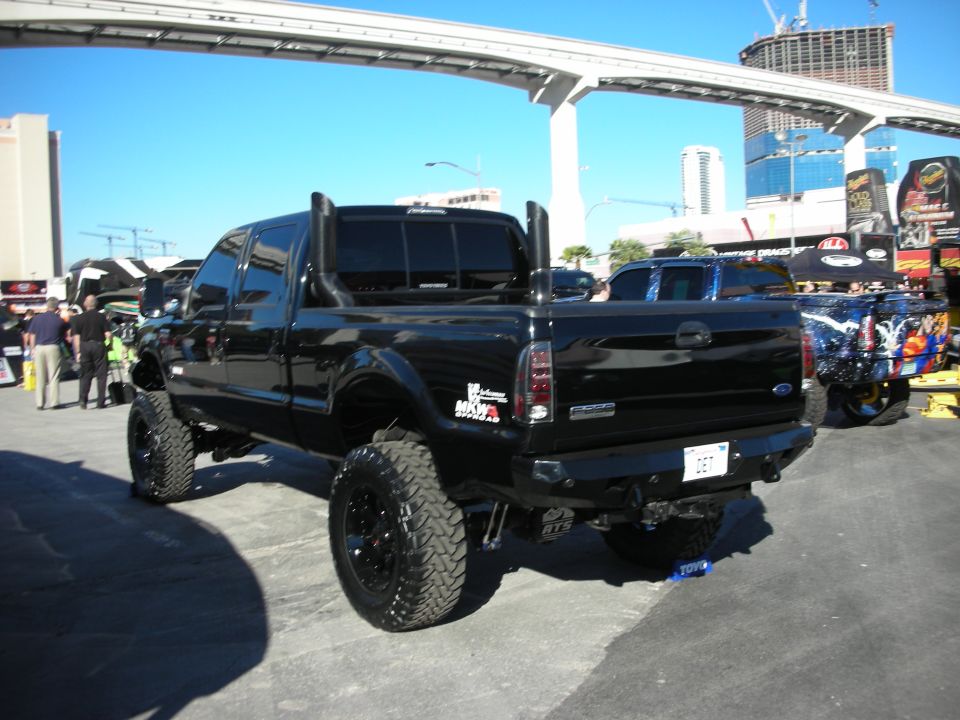 Black lifted Ford F-250 Super Duty truck, rear view, with dual exhaust stacks and custom wheels