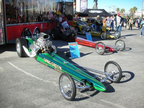 1998 Ford Crown Victoria - Multiple dragsters are displayed at an outdoor event, with spectators and tents in the background.