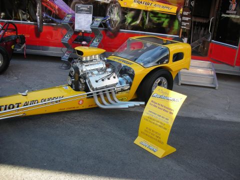 1998 Ford Crown Victoria - A dragster with a prominent V8 engine is displayed with informational signage.
