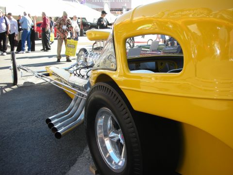 1998 Ford Crown Victoria - A bright yellow dragster is shown from the side, a prominent engine and multiple exhaust pipes.
