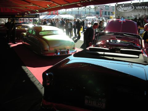 1998 Ford Crown Victoria - A scene of classic cars on display at an indoor event, with spectators observing the vehicles.