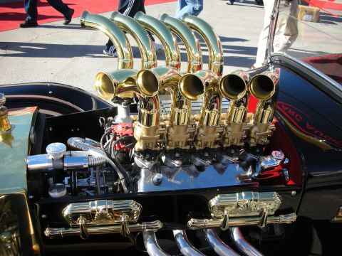 1998 Ford Crown Victoria - A highly customized V8 engine with multiple gold exhaust pipes and chrome detailing is showcased.