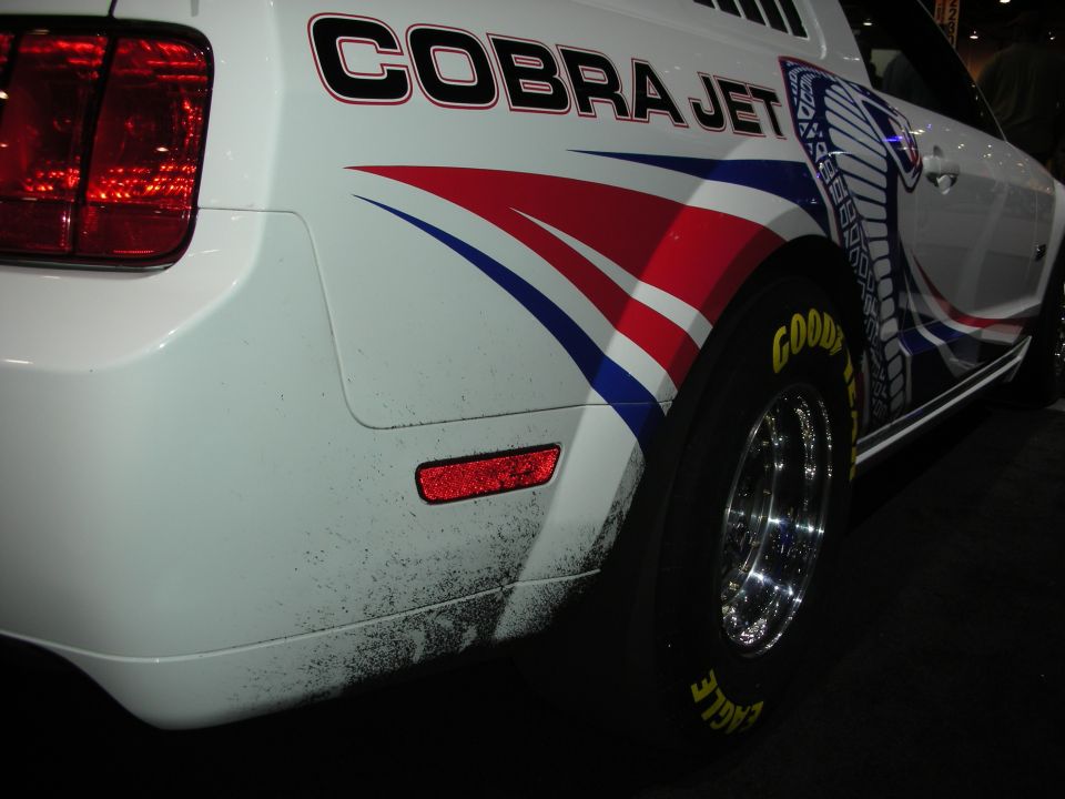 White Ford Mustang with Cobra Jet graphics and Goodyear Eagle tires, rear quarter view