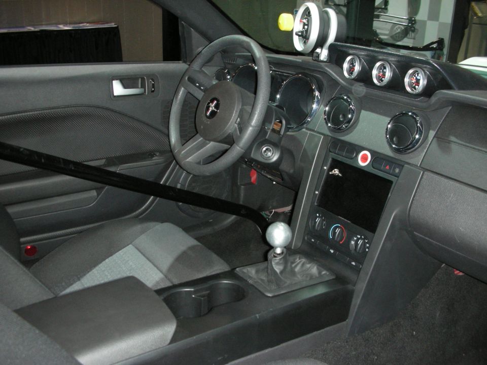Car interior with roll cage, aftermarket gauges, and manual shifter