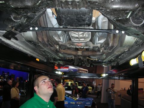 1998 Ford Crown Victoria - A view of a vehicle's undercarriage, with onlookers observing from below at an event.