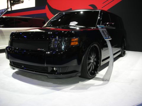 1998 Ford Crown Victoria - A modified black SUV is showcased at an event with a red graphic in the background.