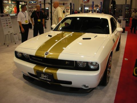 1998 Ford Crown Victoria - A white Dodge Challenger with gold racing stripes is displayed at an auto show.