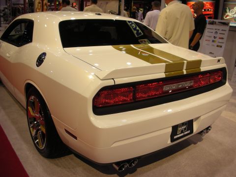 1998 Ford Crown Victoria - White Dodge Challenger with gold racing stripes and a Hurst Performance Vehicles badge is displayed at an event.