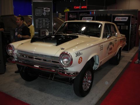 1998 Ford Crown Victoria - A white drag car with a black hood scoop and racing decals is displayed indoors on a red carpet.