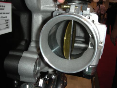 1998 Ford Crown Victoria - A close-up view of a throttle body assembly, showing the internal butterfly valve and surrounding housing.