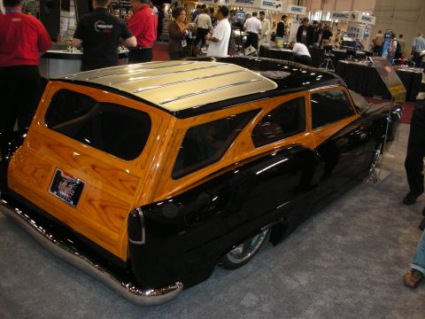 1998 Ford Crown Victoria - A custom woody wagon with a black body and wood paneling is displayed at an event.