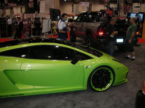 1998 Ford Crown Victoria - A lime green sports car is displayed indoors next to a pickup truck and other exhibits.