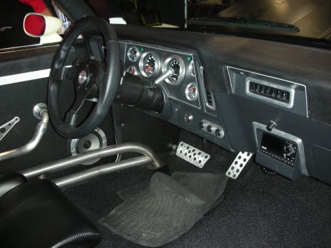 1998 Ford Crown Victoria - The interior of a modified car shows custom gauges, racing pedals, and a roll cage, indicating a performance focus.