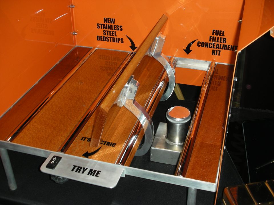 Display interior with wooden slats, metal trim, and text labels for 'New Stainless Steel Bedstrips' and 'Fuel Filler Concealment Kit'
