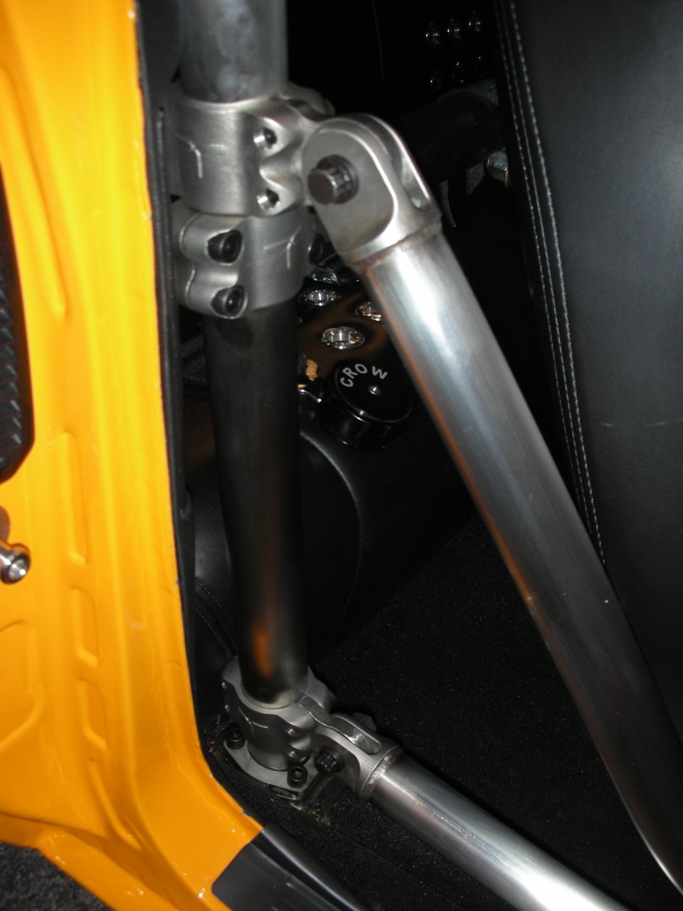 Orange interior panel with silver roll cage components and black seat. A black cap with 'CROW' is visible