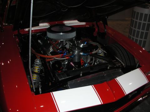 1998 Ford Crown Victoria - Engine bay of a red car white racing stripes and a prominent chrome air filter.