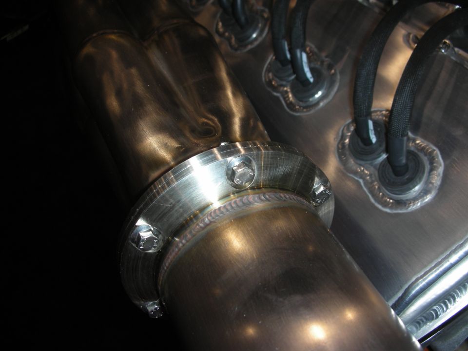 Close-up of a bolted exhaust manifold flange with black wiring harnesses