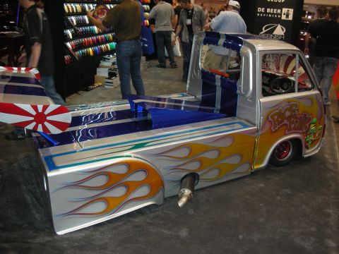 1998 Ford Crown Victoria - A highly customized mini truck with flame paint and a unique rear spoiler is displayed indoors.