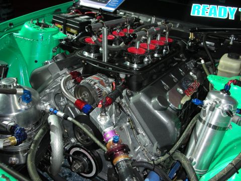 1998 Ford Crown Victoria - A highly modified V8 engine with custom intake and fuel systems is visible in a green engine bay.