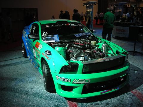 1998 Ford Crown Victoria - A modified Ford Mustang is displayed with its engine exposed, numerous sponsor decals.