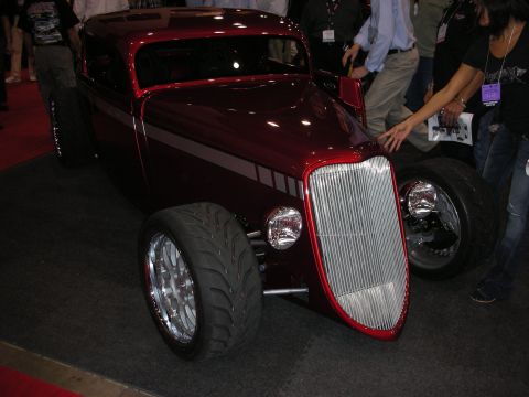 1998 Ford Crown Victoria - A custom hot rod coupe with a prominent chrome grille and red accents is displayed indoors.