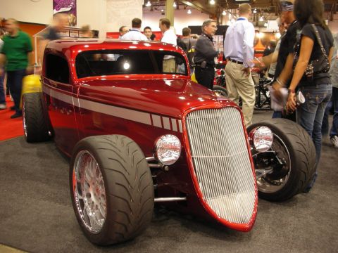 1998 Ford Crown Victoria - A custom hot rod coupe with a prominent chrome grille and wide tires is displayed indoors.