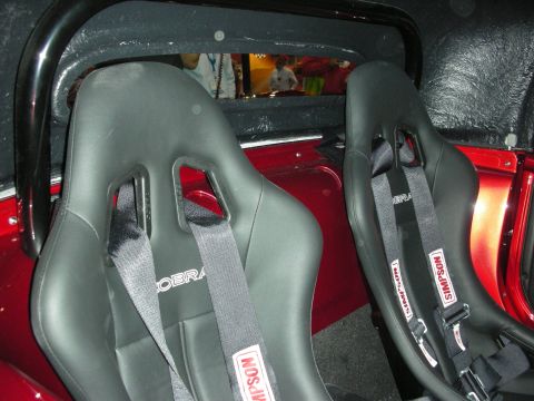 1998 Ford Crown Victoria - Two racing seats with Simpson and Cobra branding are visible inside a red vehicle.
