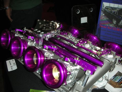 1998 Ford Crown Victoria - A custom engine intake manifold with multiple purple intake trumpets is displayed, with a sign in the background referencing SEMA Days.