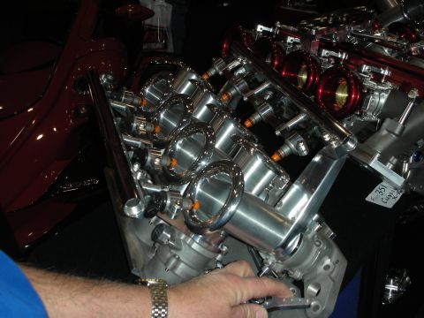 1998 Ford Crown Victoria - A highly customized V8 engine with polished aluminum intake runners and red accents is displayed, with a partial view of a dark red vehicle…