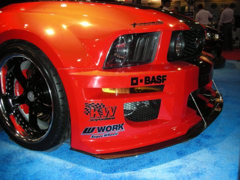 1998 Ford Crown Victoria - A red sports car with custom decals is displayed indoors on a blue carpeted floor.