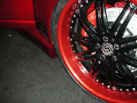 1998 Ford Crown Victoria - Close-up of a red vehicle's custom wheel and side panel, showing intricate detailing.