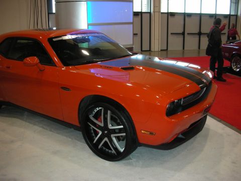 1998 Ford Crown Victoria - Orange Dodge Challenger with black racing stripes and custom wheels on display.