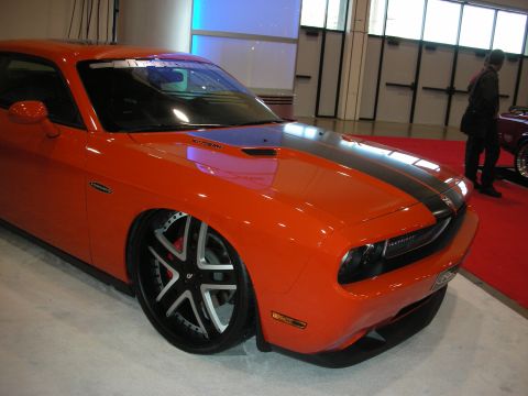 1998 Ford Crown Victoria - A bright orange Dodge Challenger is displayed with custom wheels and a lowered stance.