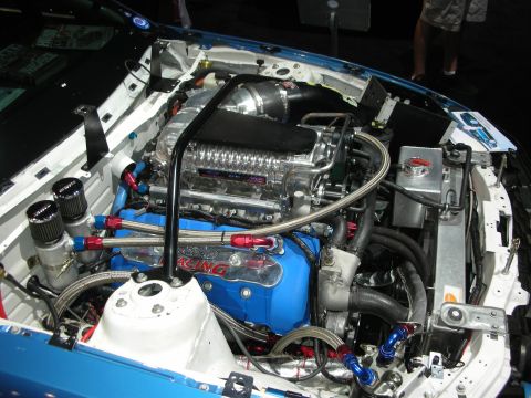 1998 Ford Crown Victoria - Customized engine bay with a prominent supercharger and blue Ford Racing valve covers.
