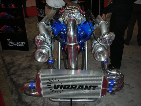 1998 Ford Crown Victoria - Custom twin-turbocharged V8 engine assembly with a Vibrant Performance intercooler displayed at an event.