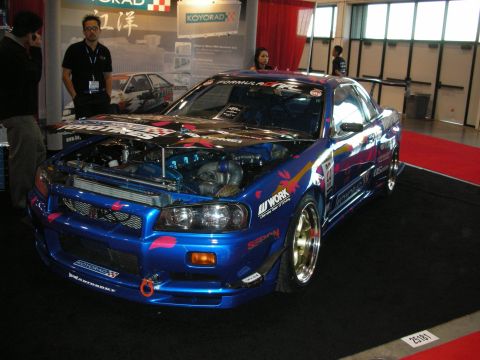 1998 Ford Crown Victoria - Modified blue sports car on display, engine exposed with turbocharger visible.