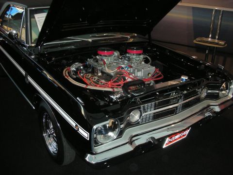 1998 Ford Crown Victoria - A black muscle car is displayed with its hood open, revealing a powerful engine with dual carburetors.