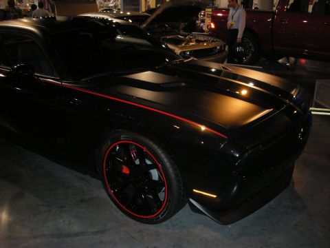 1998 Ford Crown Victoria - A black Dodge Challenger with red racing stripes and custom wheels is displayed indoors.