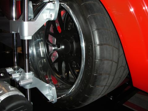 1998 Ford Crown Victoria - Close-up of a red car's wheel and tire being serviced by an alignment machine.