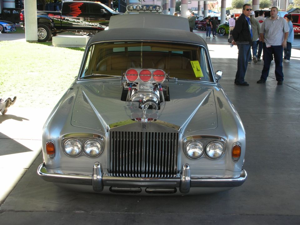 Silver Rolls-Royce with a prominent supercharger and triple carburetors, hood open, front view