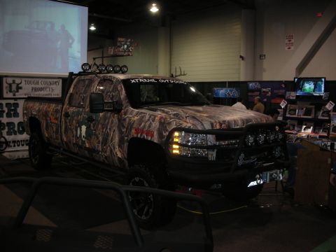 1998 Ford Crown Victoria - A pickup truck with a camouflage wrap is displayed indoors with promotional materials.