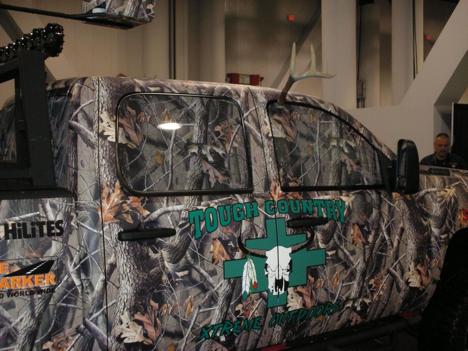 Camouflaged truck with deer antlers on the roof and "Tough Country Xtreme Outdoors" graphics