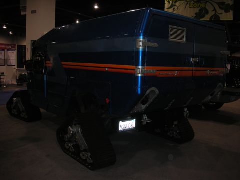 1998 Ford Crown Victoria - A unique vehicle with tracks instead of wheels is displayed indoors.