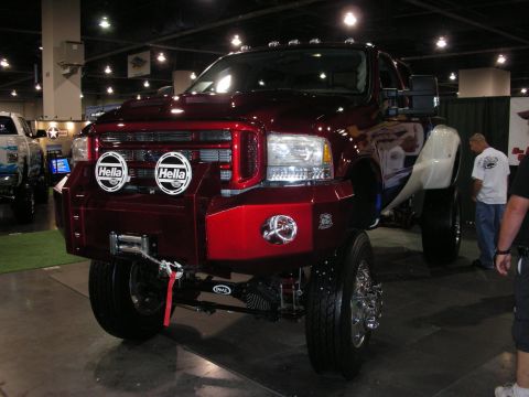 1998 Ford Crown Victoria - A heavily customized red Ford Super Duty truck is displayed indoors, with another truck partially visible to its left.
